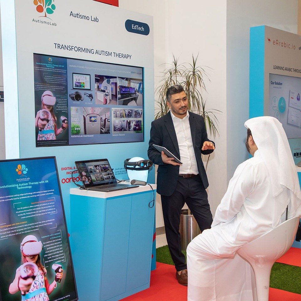 Akram Hidri presenting AutismoLab at an exhibition booth under a banner reading Transforming Autism Therapy